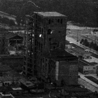 Overhead view of a city, possibly post-war, with dense buildings.