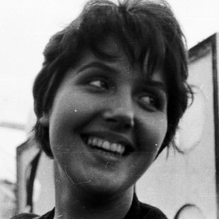 Here's a brief summary: Smiling woman with short hair, black and white portrait.