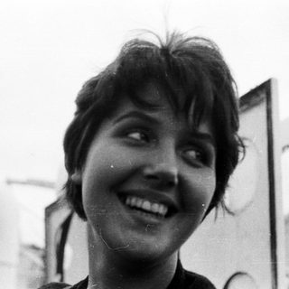 Here's a brief summary: Smiling woman with short hair, black and white portrait.