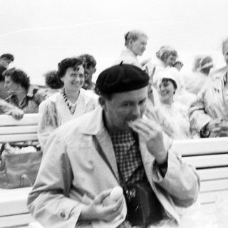 Group of people on a bench, likely at the seaside.