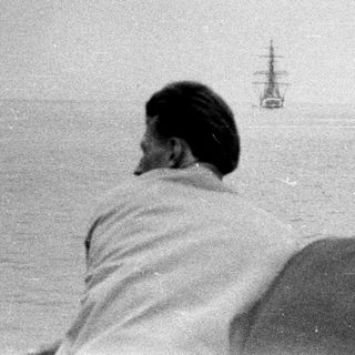 People watch a distant ship at sea.