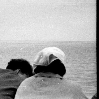 People watch a distant ship at sea.