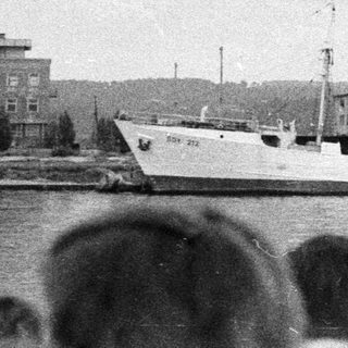 Ship docked at harbor, viewed from across the water.