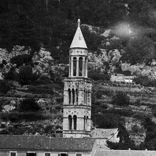 Building with tower near water, backed by hillside.