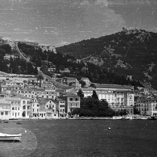 Coastal town nestled between mountains with boats in the water.