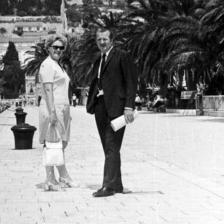 Couple stands on a pier, overlooking a hillside town.