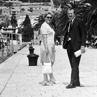 Couple stands on a pier, overlooking a hillside town.