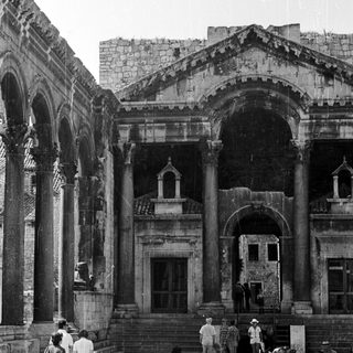 Black and white image of ancient ruins with people.