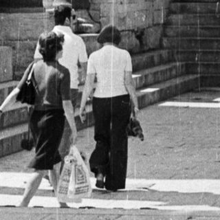 Black and white image of ancient ruins with people.