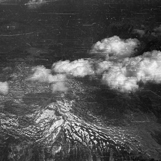 Aerial view of a snow-covered mountain and clouds.