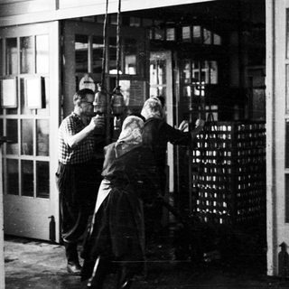 Men appear to be moving stacked bottles through a doorway.