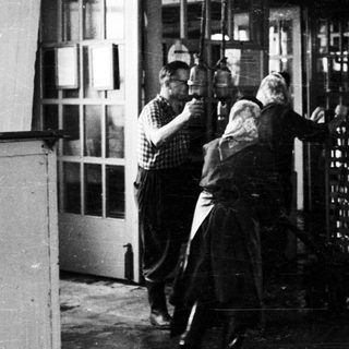 Men appear to be moving stacked bottles through a doorway.