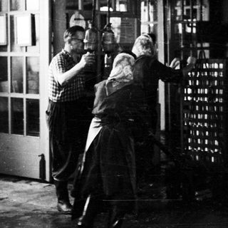 Men appear to be moving stacked bottles through a doorway.