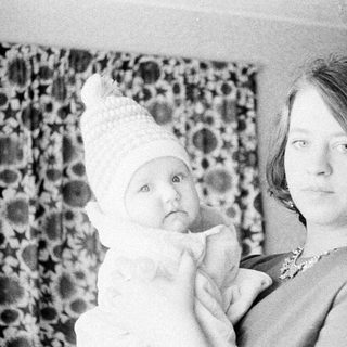 Woman holding baby, wearing a decorative hat.