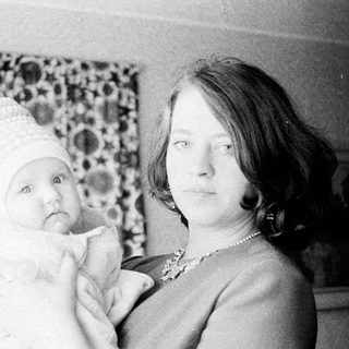 Woman holding baby, wearing a decorative hat.