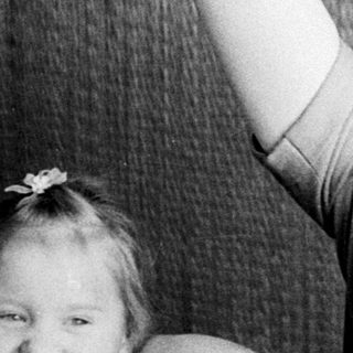 Woman with arms behind her head, child nearby.