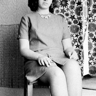 Woman seated in a dress, posing for a portrait.