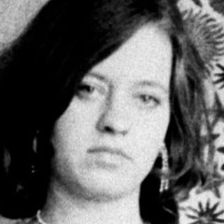 Woman seated in a dress, posing for a portrait.
