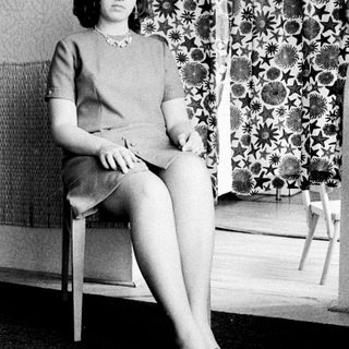 Woman seated in a dress, posing for a portrait.