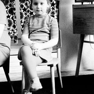 Black and white photo of a young girl sitting on a chair.