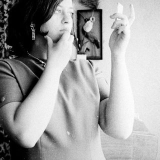 Woman looking in a mirror, examining her face.