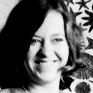 Woman sits in chair, posing in a black and white photograph.