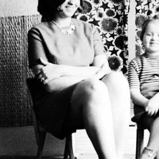 Woman and child seated, smiling, in a vintage interior.