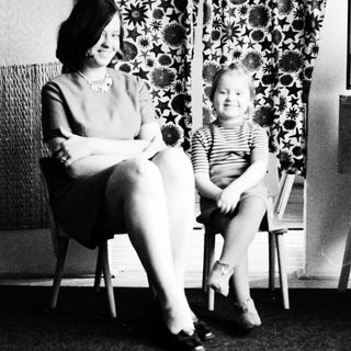 Woman and child seated, smiling, in a vintage interior.