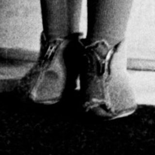 Black and white photo of a young girl standing indoors.