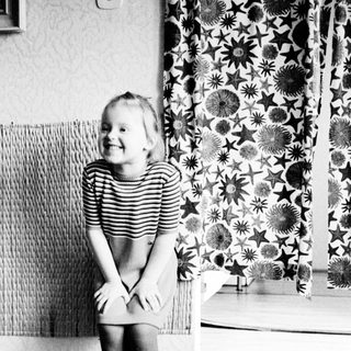 A young girl sits smiling, facing away from the camera.