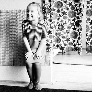 A young girl sits smiling, facing away from the camera.