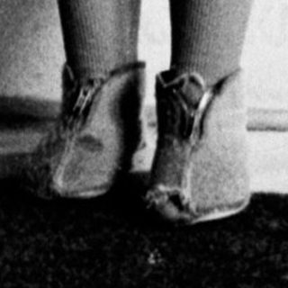 Young girl stands near a curtain in a room.