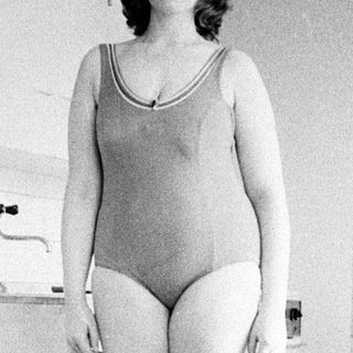 Woman in a swimsuit stands in a vintage bathroom.
