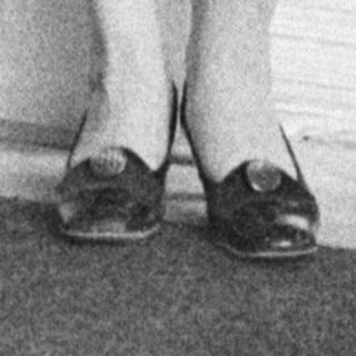 Woman in a dress stands with arm raised, indoors.
