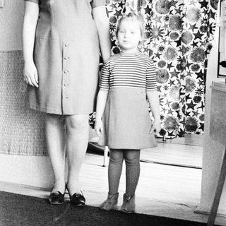Woman and child stand in front of patterned curtain.