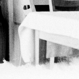 Woman in leotard poses near a door and table.