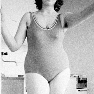 Woman in swimsuit standing in a vintage bathroom.