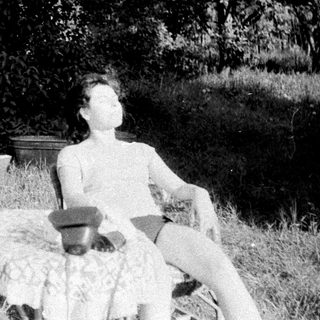 Two people relax outdoors, one reading, in a grassy area.