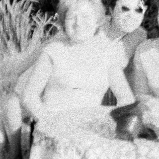 Two women seated in tall grass, outdoors.