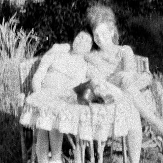 Three children standing in tall grass, blurred image.