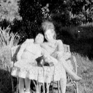 Three children standing in tall grass, blurred image.