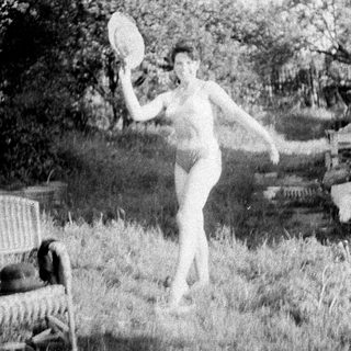 Woman playfully tossing a plate in a grassy yard.