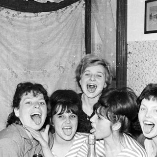 Group of women playfully sticking out their tongues.