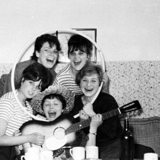 Group of women playing instruments and laughing indoors.