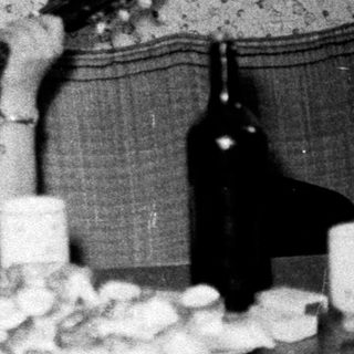 Person playing guitar with drinks and snacks on table.