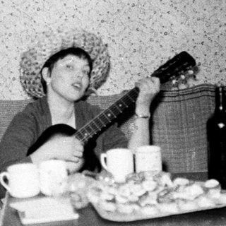 Person playing guitar with drinks and snacks on table.
