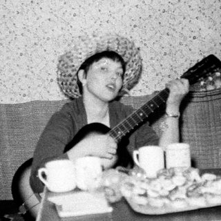 Person playing guitar with drinks and snacks on table.