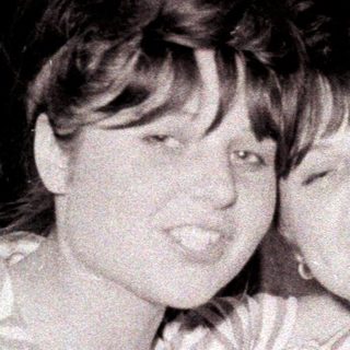 Two smiling women embrace in a vintage black and white photo.
