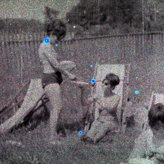 Here's a brief summary of the image: Group of children sitting and playing near a fence.