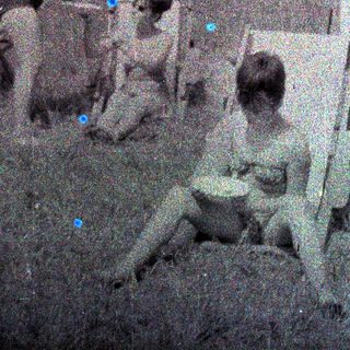Here's a brief summary of the image: Group of children sitting and playing near a fence.